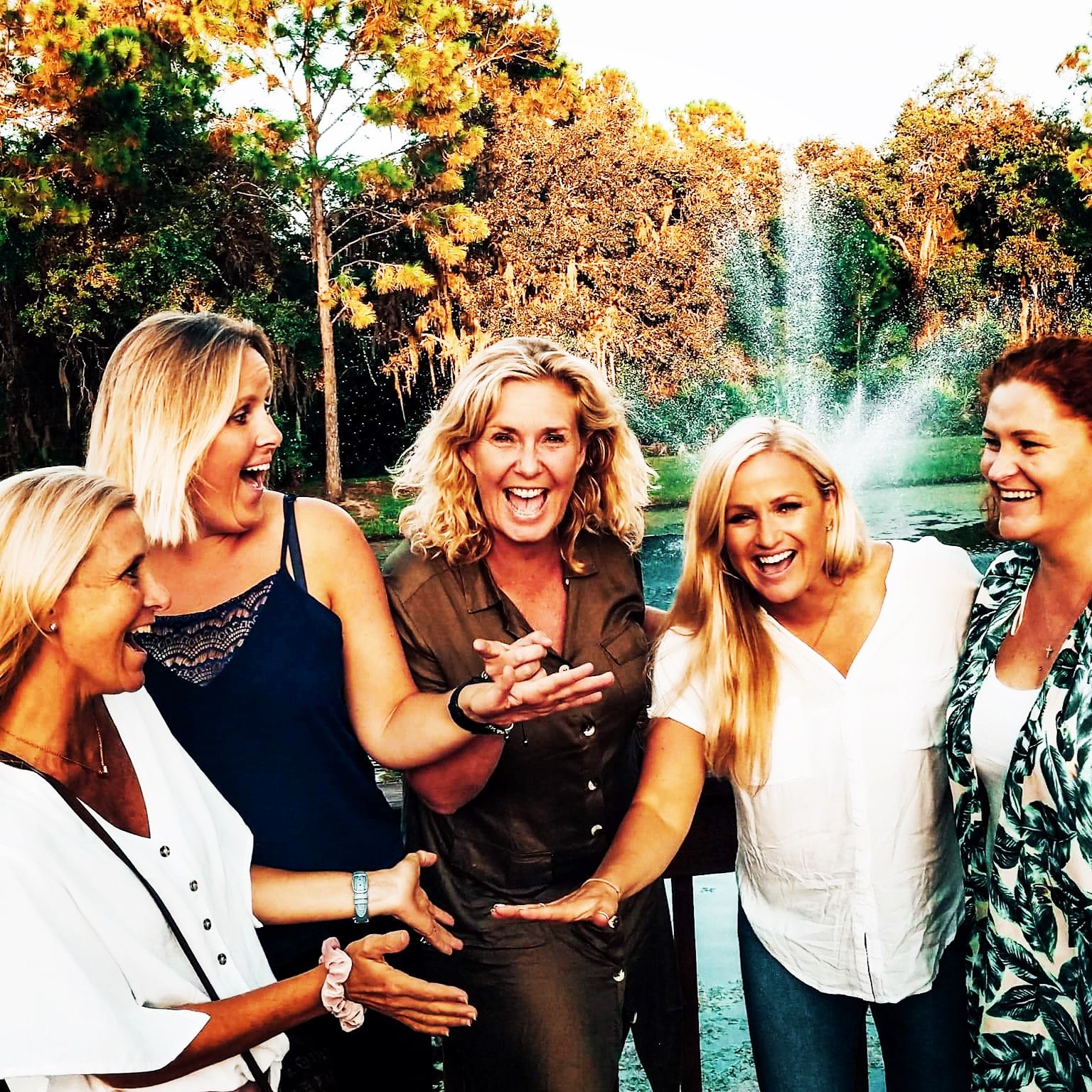 Five team members laughing together by a fountain